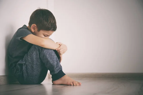 Pequeno menino triste sentado no chão em casa — Fotografia de Stock