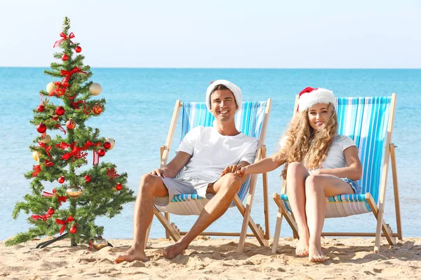 Ungt par och julgran på stranden — Stockfoto