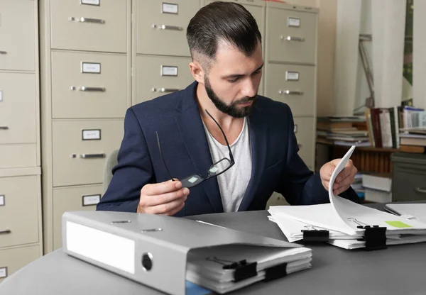 Young man working with documents at table in archive