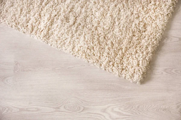 Biały puszysty dywan na podłogę drewnianą, zbliżenie — Zdjęcie stockowe