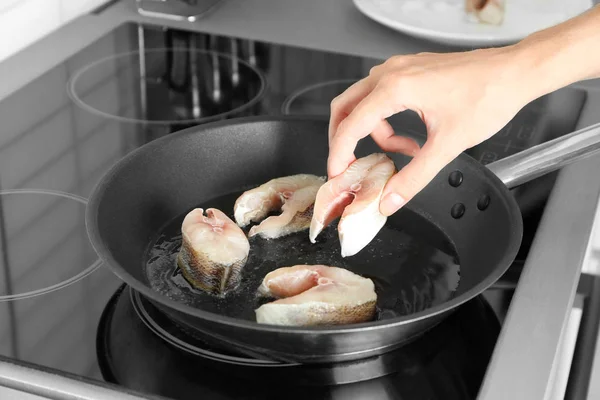 Donna che frigge bistecche di pesce su pentola in cucina — Foto Stock