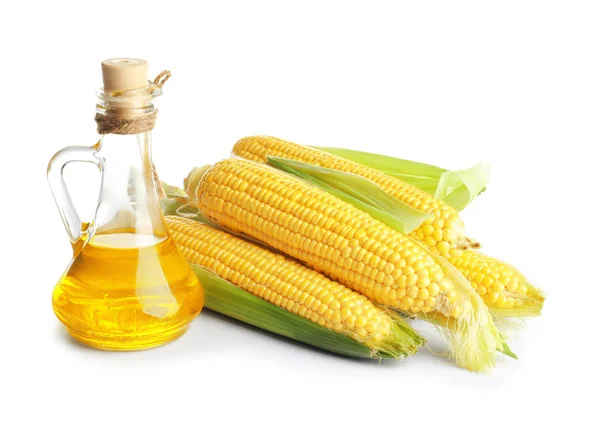 Glass pitcher with corn oil and ripe cobs — Stock Photo, Image
