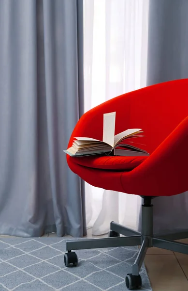 Chair with book near beautiful curtains indoors — Stock Photo, Image