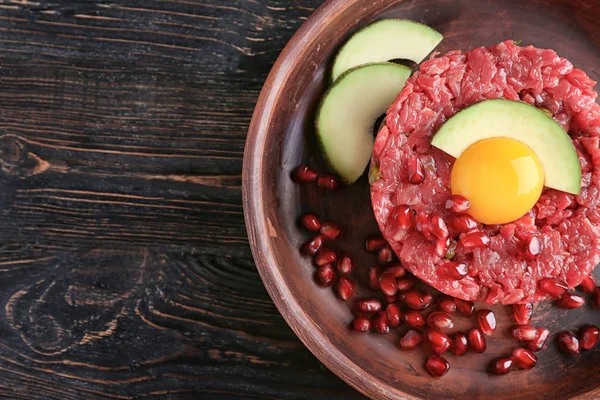 Delicious steak tartare with yolk, avocado and pomegranate seeds on plate — Stock Photo, Image
