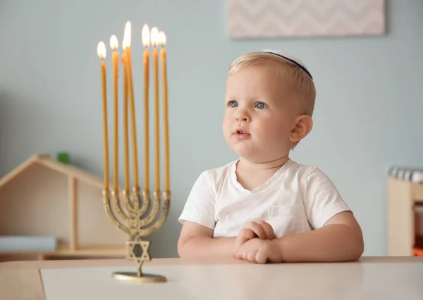 Leuke jongen zitten in de buurt van negen-vertakt menora op tafel thuis — Stockfoto