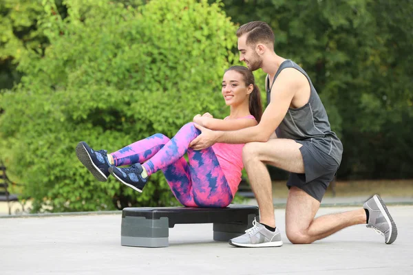 Mujer joven haciendo ejercicio con entrenador personal en el campo de deportes —  Fotos de Stock