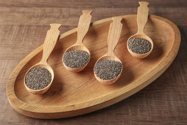 Colheres com sementes de chia em prato de madeira — Fotografia de Stock