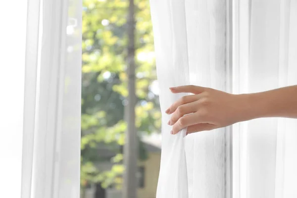 Mulher abrindo cortinas brancas — Fotografia de Stock