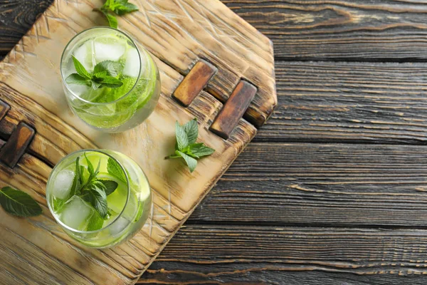 Glasses of cocktail with mint and lime on wooden board — Stock Photo, Image