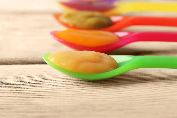 Cucchiai di plastica con alimenti per bambini — Foto Stock