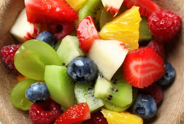 Deliciosa salada de frutas em tigela de madeira, close-up — Fotografia de Stock