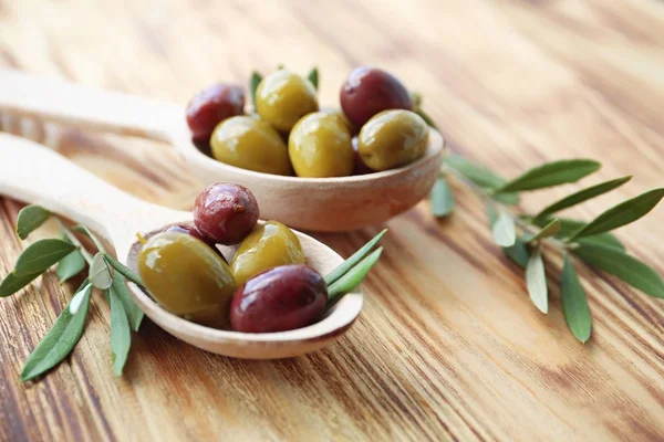Spoons with canned olives on table — Stock Photo, Image
