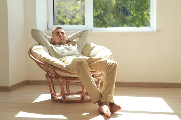 Młody mężczyzna odpoczynek w fotelu w pobliżu okna w domu — Zdjęcie stockowe
