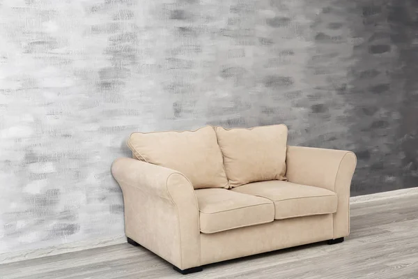 Cozy sofa on grunge wall background — Stock Photo, Image