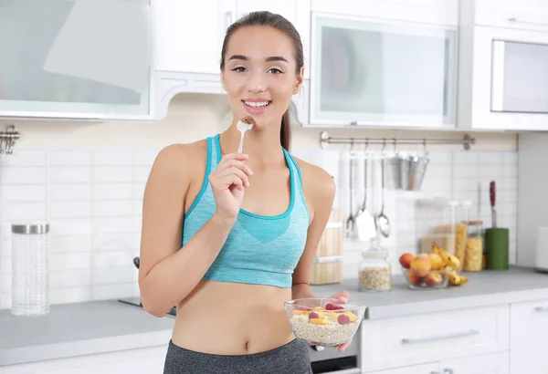 Mujer joven en ropa deportiva comiendo avena en la cocina —  Fotos de Stock