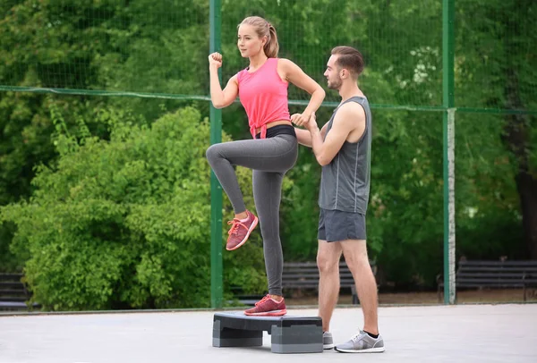 Mujer joven haciendo ejercicio con entrenador personal en el campo de deportes — Foto de Stock