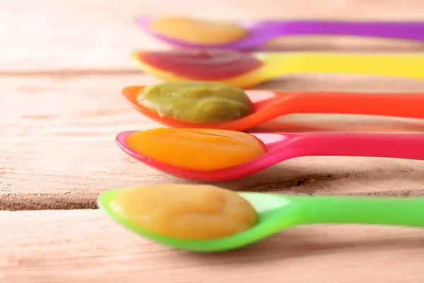 Cucchiai di plastica con alimenti per bambini — Foto Stock