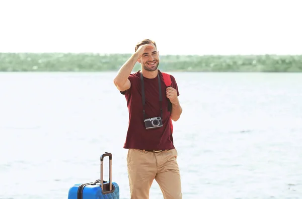Handsome young tourist with suitcase