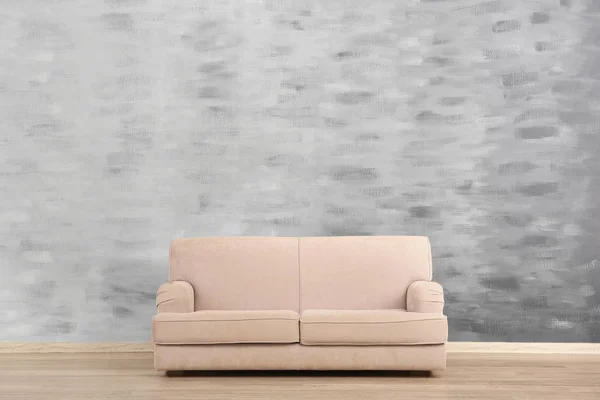 Mysig soffa på grunge vägg bakgrund — Stockfoto