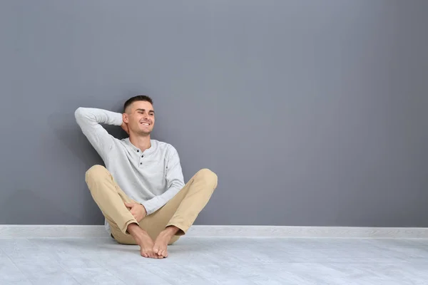 Jovem sentado no chão perto da parede cinza — Fotografia de Stock