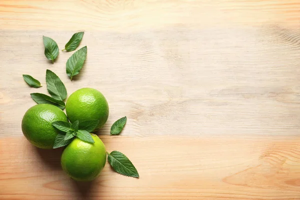 Composition with lime and mint on wooden background — Stock Photo, Image