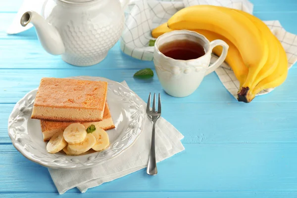 Plate with tasty banana cakes and cup of tea on wooden table — Stock Photo, Image