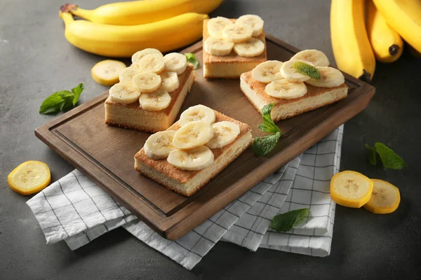 Wooden board with pieces of tasty banana cake on table — Stock Photo, Image
