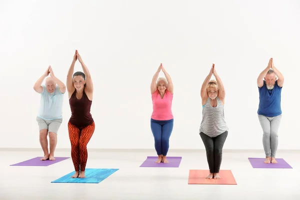 Gruppo di uomini e donne maturi a lezione di yoga al chiuso — Foto Stock