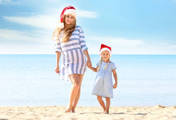 Young mother with cute girl on beach. Christmas celebration concept — Stock Photo, Image