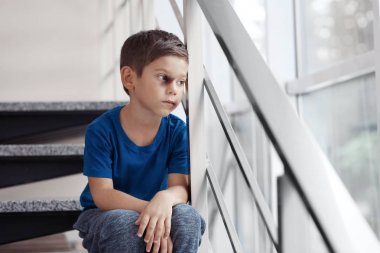 İç merdivenlerde oturan çürük olan küçük çocuk. Aile içi şiddet kavramı