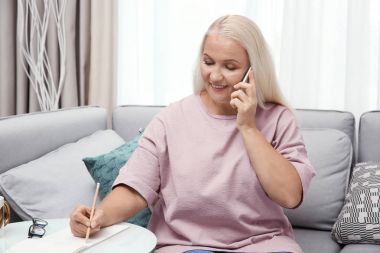 Evde cep telefonuyla konuşan kadın kıdemli