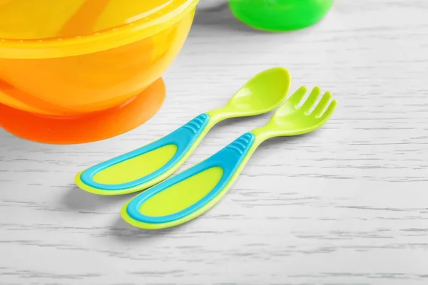 Coloridos utensilios de alimentación de plástico para el bebé en la mesa — Foto de Stock
