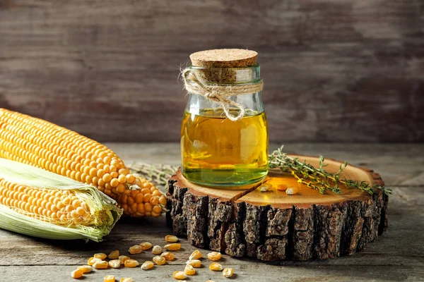Glass jar with corn oil on board — Stock Photo, Image