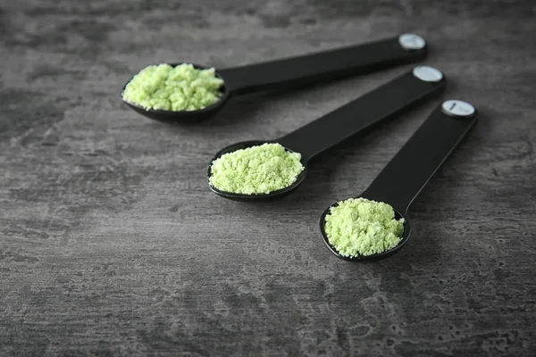 Scoops with wheat grass powder on table