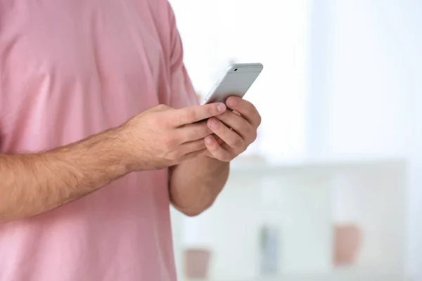 Homem segurando smartphone dentro de casa — Fotografia de Stock