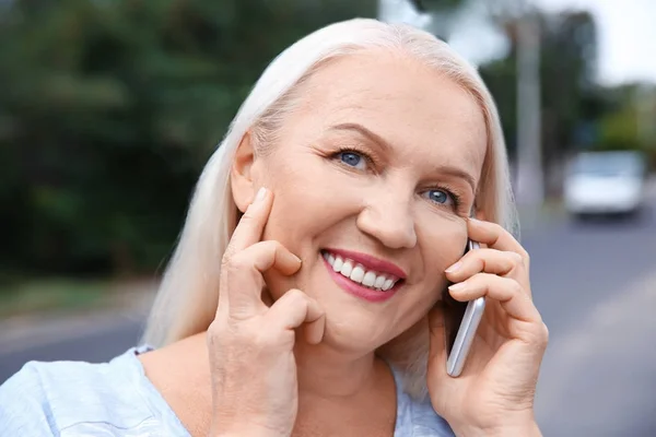 Senior woman speaking on cell phone outdoors — Stock Photo, Image