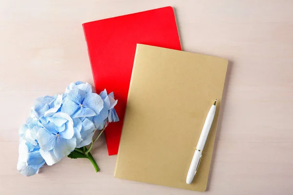 Beautiful blue flowers, notebooks and pen — Stock Photo, Image