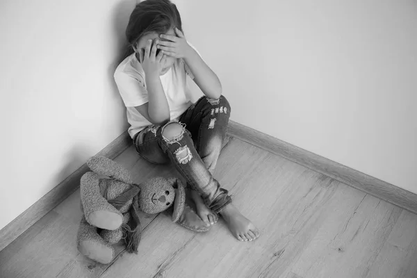 Ijedt kis lány ül a szoba sarkában. Családon belüli erőszak fogalma — Stock Fotó