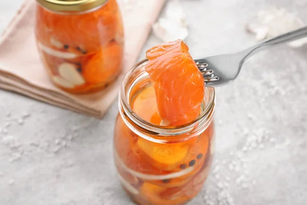 Fork and jar with delicious marinated salmon — Stock Photo, Image