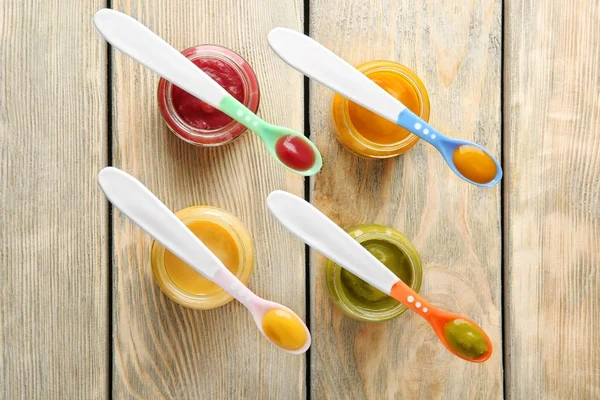 Cucchiai e barattoli di plastica con alimenti per bambini — Foto Stock