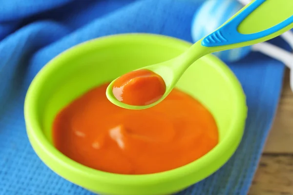 Plastic spoon and bowl with baby food