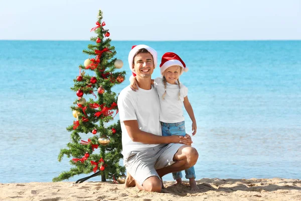 Jovem pai com linda menina e árvore de Natal na praia — Fotografia de Stock