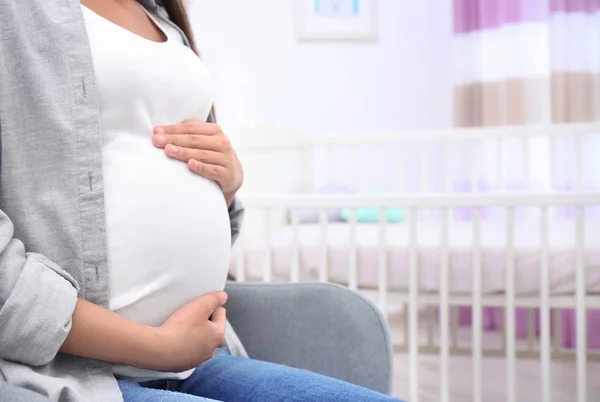 Беременная женщина сидит в детской комнате — стоковое фото