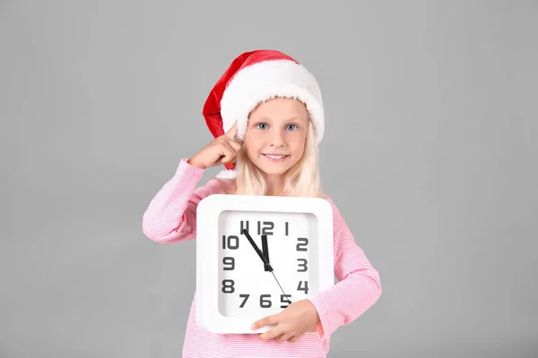 可爱的女孩在圣诞老人帽子与时钟灰色背景。圣诞倒计时概念 — 图库照片