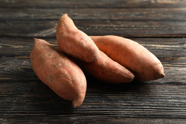 Zoete aardappelen op houten achtergrond — Stockfoto