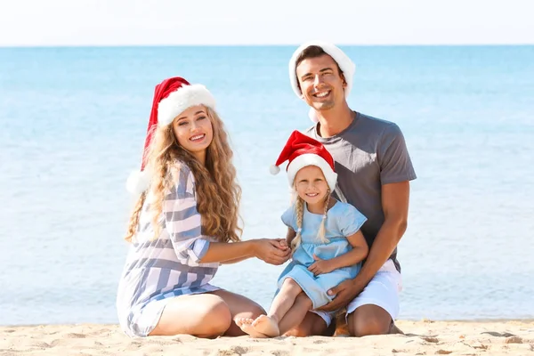 Młoda para z słodkie dziewczyny na plaży. Boże Narodzenie celebracja koncepcja — Zdjęcie stockowe