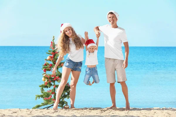 Família feliz e árvore de Natal na praia — Fotografia de Stock