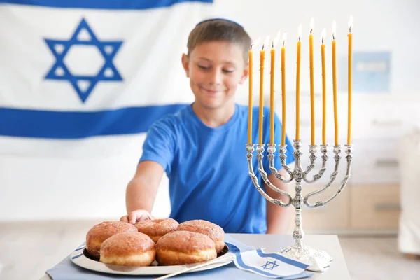 Joodse jongen met traditionele sufganiyah thuis — Stockfoto