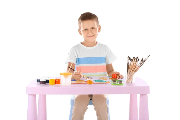 Talentueux garçon peinture tandis que assis à la table sur fond blanc — Photo