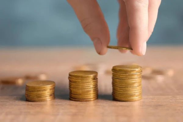 Mujer apilando monedas sobre fondo borroso, primer plano — Foto de Stock